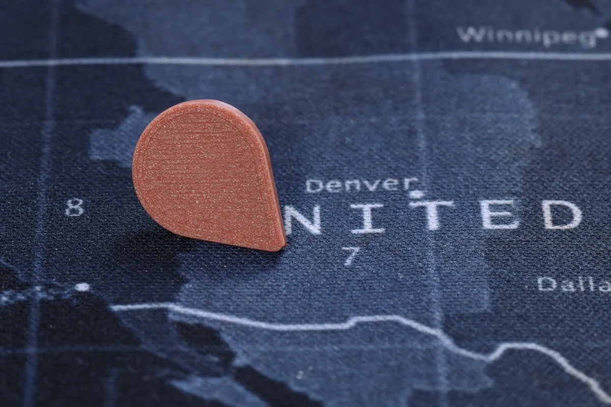 A terracotta Touch-to-Travel pin in a fabric world map over the United States