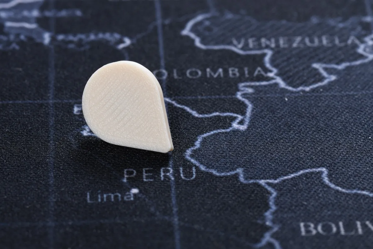 A white Touch-to-Travel pin in a fabric map over Peru